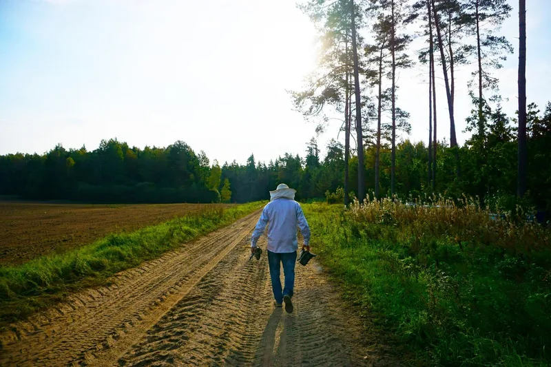 Beekeeper walking on a rural path in the Lithuanian countryside